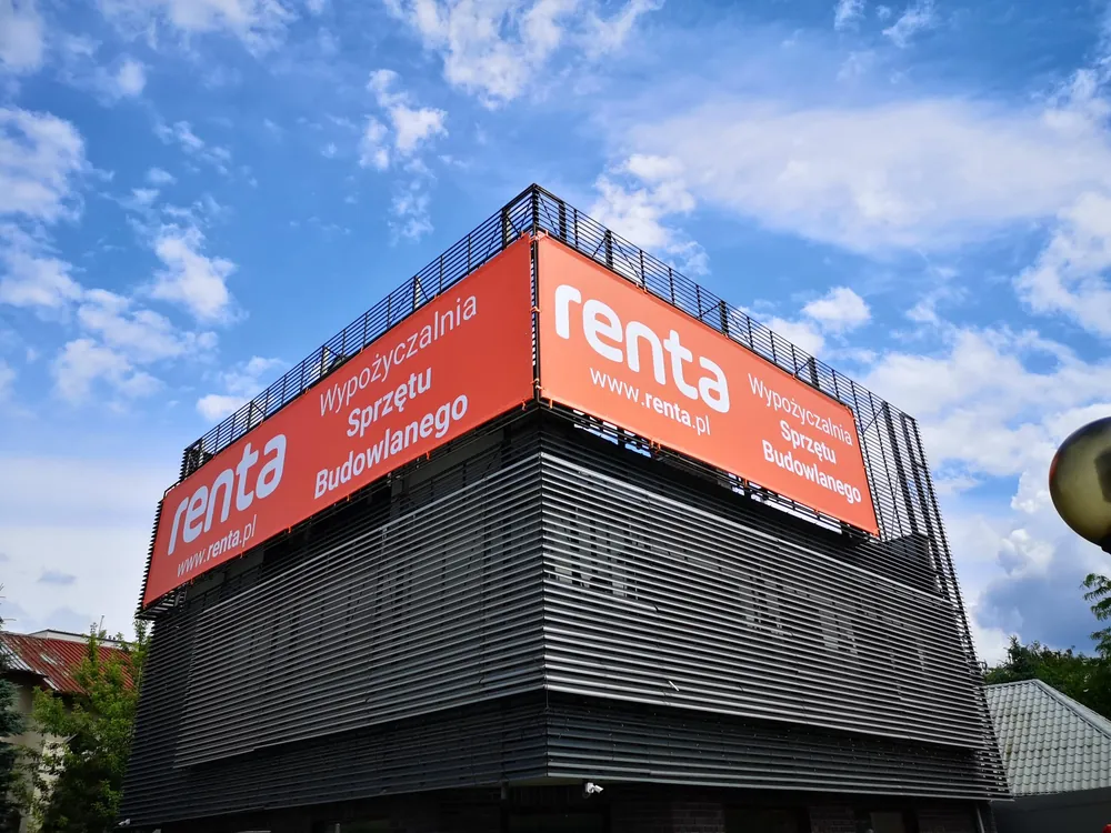Baner reklamowy z nazwą firmy zamontowany na elewacji budynku