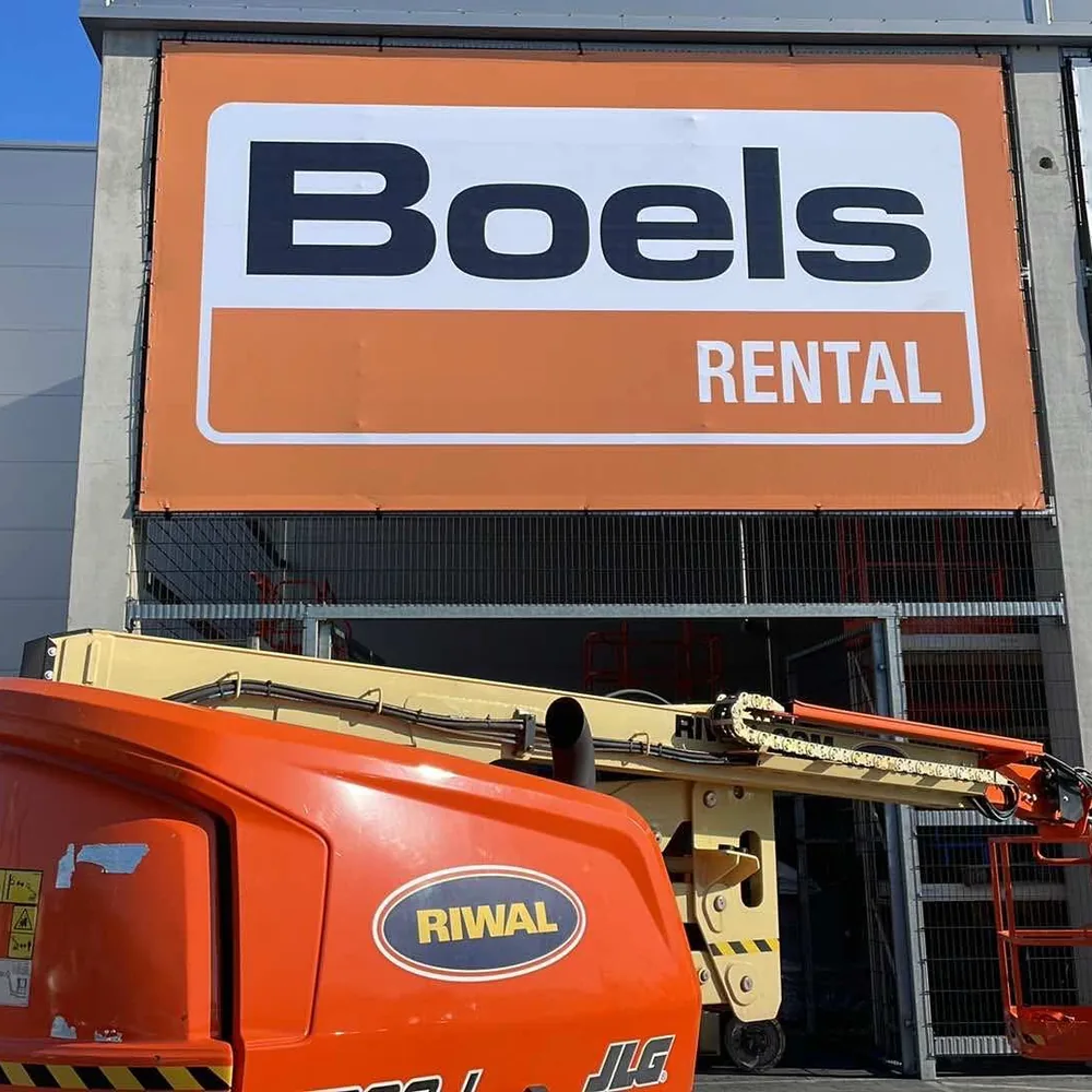 Baner Boels Rental na elewacji, montaż z podnośnika