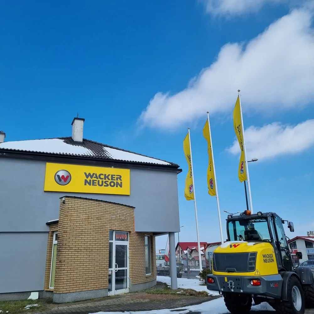 Oddział Wacker Neuson z szyldem na elewacji i flagami