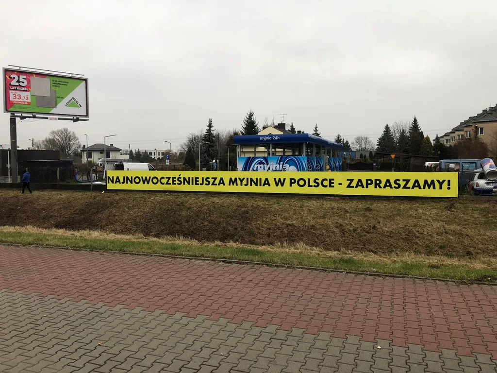 Baner reklamowy myjni zamontowany na ogrodzeniu
